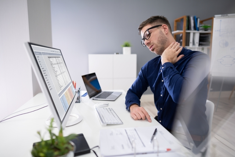 Person at desk experiencing neck and back pain